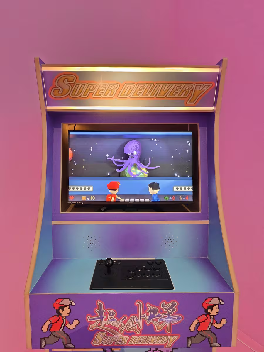 Ein verzierter Arcade-Automat in Violett und Gold in einem rosa beleuchteten Korridor.