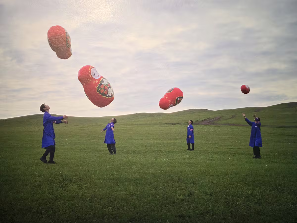Videobild mit vier Kindern, roten Ballons und einer Stadtsilhouette hinter einer Wiese.